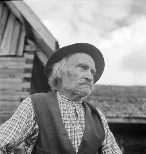 Henkilökuva vanhemmasta miehestä jolla on hattu päässä ja joka katsoo kaukaisuuteen 