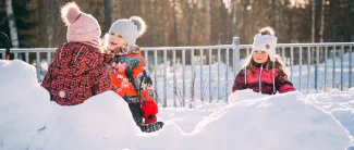 Lapset leikkii päiväkodin pihalla talvella.