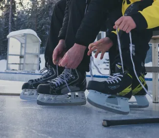 Luistimien nauhojen kiinni laittoa jäällä.