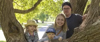 Äiti, isä ja kaksi lasta puiden keskellä.