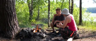 Nainen ja mies nuotiolla kahvilla.