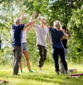 Henkilöitä antamassa ylävitosia luonnossa urheilun parissa.