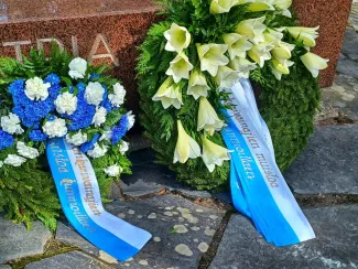 Kaksi kukkaseppelettä muistomerkillä.