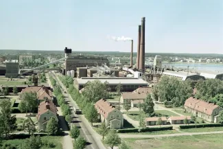 Varkauden maisema kesäinen kirkon tornista kuvattuna etualalla puisia asuinrakennuksia taustalla Varkauden tehtaat ja sen kolme piippua joista tulee savua 