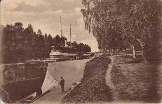 Vanha postikortti Taipaleen kanavalta ruskeasävyinen kuva jossa näkyy Taipaleen kanavan sulku ja yksi ihminen seisomassa kanavan laidalla